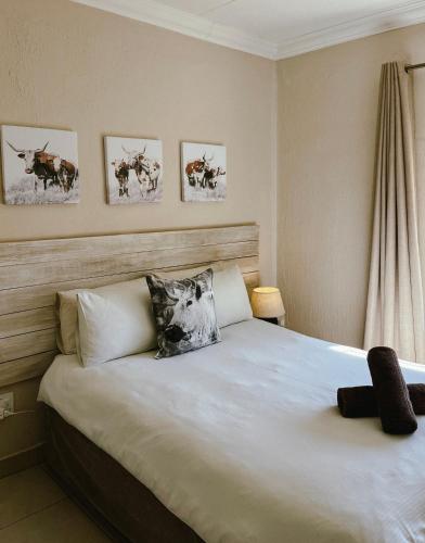 a bedroom with a large bed with four pictures on the wall at Rondebossie Farm Retreat in Magoebaskloof