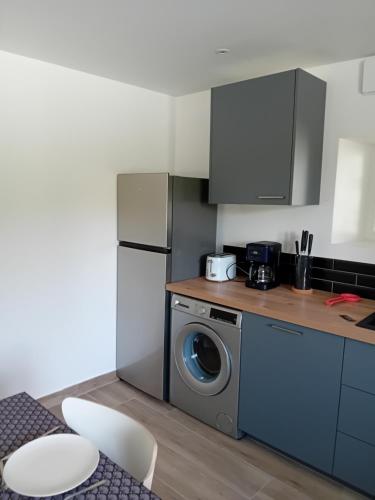 une cuisine avec un réfrigérateur et une machine à laver dans l'établissement Maison du Potager de Puy Marot, à Feytiat