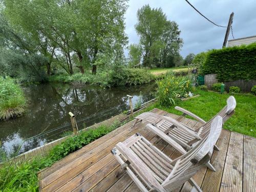 2 chaises assises sur une terrasse en bois à côté d'une rivière dans l'établissement Coin de paradis idéal nature, à Houlle