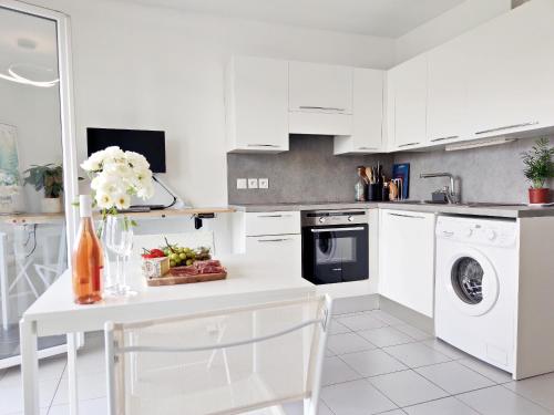 - une cuisine avec des placards blancs et une table fleurie dans l'établissement Bright & calm sea-view apartment, à Antibes