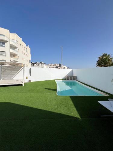 un cortile con prato verde e una piscina di Hospedería Almundo by Alexandra Realty a Tarifa