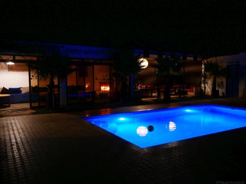 a blue swimming pool at night in front of a building at Dar Iziki in Sidi Kaouki