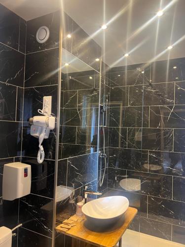 a black tiled bathroom with a toilet and a sink at Hôtel De La Perdrix Rouge in Paris