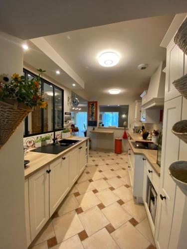 Il comprend une grande cuisine avec des placards blancs et du carrelage. dans l'établissement Les Capucines, à LʼIsle-sur-la-Sorgue