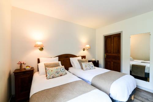 a bedroom with two beds and a mirror at Logis Hôtel Etchemaïté in Larrau