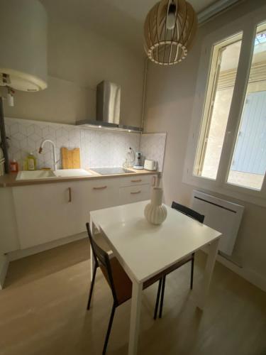 une cuisine avec une table et des chaises blanches ainsi qu'une fenêtre dans l'établissement LE Zen, à Nîmes