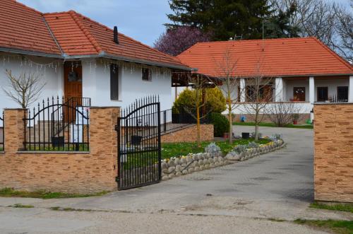 a white house with a red roof and a gate at Kerekerdő Vendégház in Kisszékely