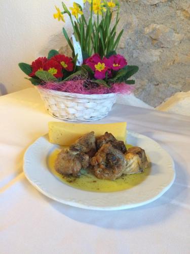 a plate of food on a table with a basket of flowers at Rifugio Pranolz in Trichiana