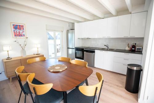 une cuisine et une salle à manger avec une table et des chaises en bois dans l'établissement KER PIRAH Appartement proche des plages centre carnac plage, à Carnac