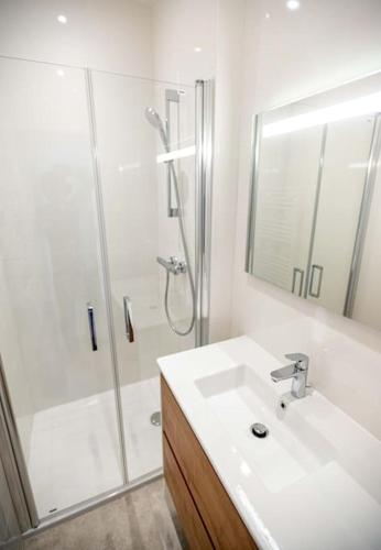une salle de bain blanche avec un lavabo et une douche dans l'établissement KER PIRAH Appartement proche des plages centre carnac plage, à Carnac