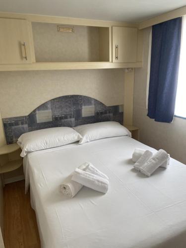 a large white bed with two folded towels on it at Baia del Principe MobilHome in Oliveri