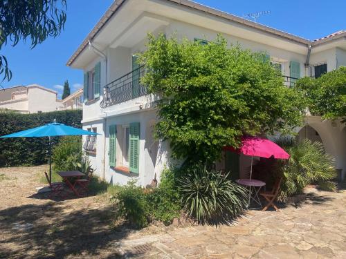 une maison avec deux tables et un parasol dans l'établissement Chez Madou, T1 en bas de villa et rez de jardin à 900m de la mer et des commerces, à Fréjus