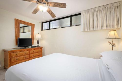a bedroom with a white bed and a tv at Aston at Papakea Resort in Lahaina