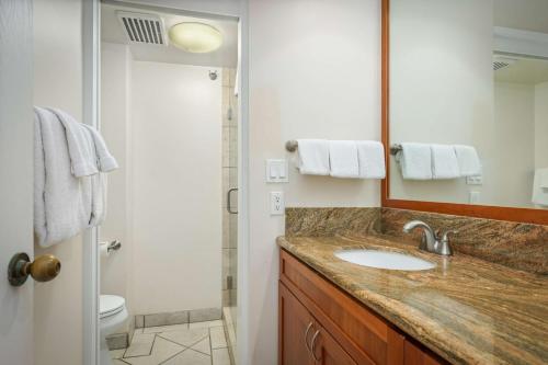 a bathroom with a sink and a toilet and a mirror at Aston at Papakea Resort in Lahaina