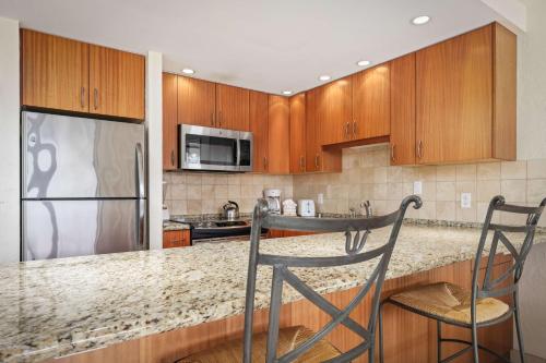 a kitchen with wooden cabinets and a granite counter top at Aston at Papakea Resort in Lahaina