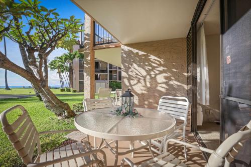 a white table and chairs on a patio with a tree at Aston at Papakea Resort in Lahaina