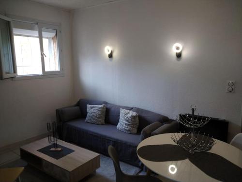 un salon avec un canapé bleu et une table dans l'établissement Appartement cosy, à Saint-Laurent-de-la-Salanque