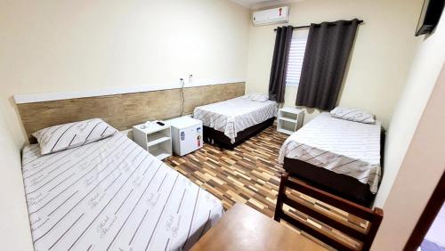 a room with two beds and a table in a room at Florence Hotel in Sao Paulo