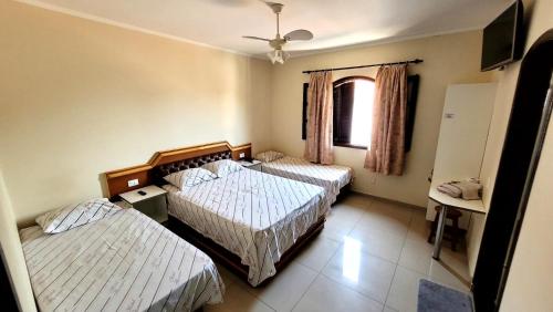 a bedroom with two beds and a window and a tv at Florence Hotel in Sao Paulo