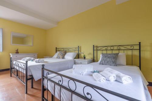 two beds in a room with yellow walls at Italian Experience- Villa La Pagliarina in Cartoceto