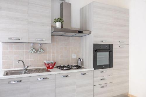 a kitchen with white cabinets and a sink and a stove at Italian Experience- Maison Loreto in Loreto