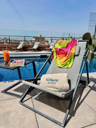 a lounge chair sitting next to a swimming pool at Silken Ramblas in Barcelona