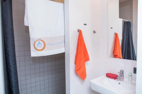 Antwerp Central Youth Hostel في أنتويرب: حمام مع منشفة برتقالية معلقة على الحائط