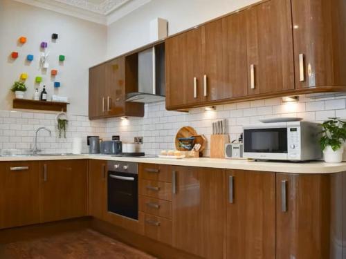 a kitchen with wooden cabinets and a microwave at Strathmore apt Scarborough, pool, gym, parking in Scarborough