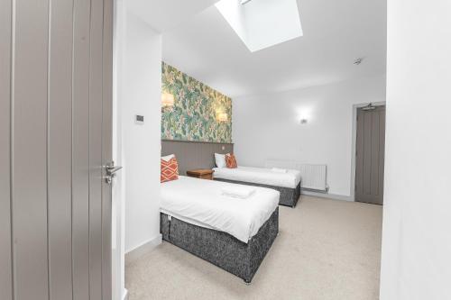a bedroom with two beds and a painting on the wall at The Redwell Country Inn in Arkholme