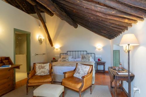 a bedroom with a bed with two chairs and a table at Hotel Boutique Molino del Arco in Ronda