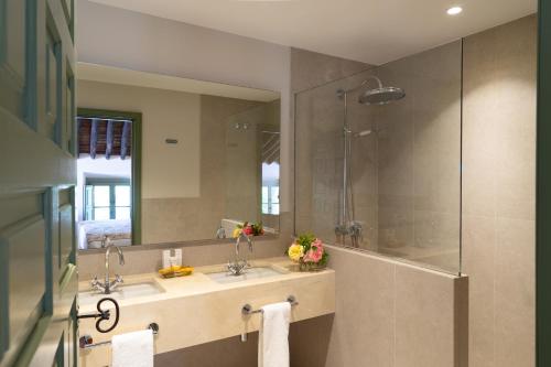 a bathroom with two sinks and a shower with a mirror at Hotel Boutique Molino del Arco in Ronda