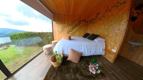 a bedroom with a bed and a large window at Refugio del Neusa in Cogua