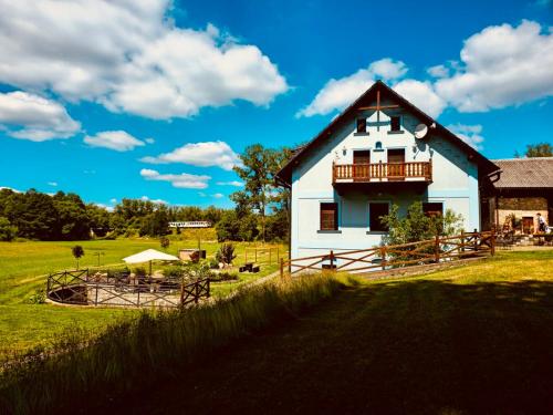 a white house with a balcony on a green field at Penzion Stanský Mlýn in Hlinsko