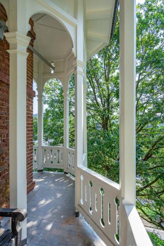 a porch with white columns and windows and trees at Château Constance, 19 personnes in La Roche-en-Ardenne