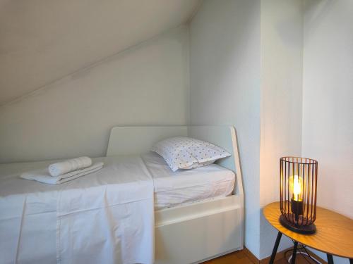 a small white bedroom with a bed and a table at Croatia Home in Velika Gorica