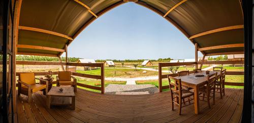 a wooden deck with a table and chairs in a tent at AgriGlamping Munai in San Giovanni Suèrgiu