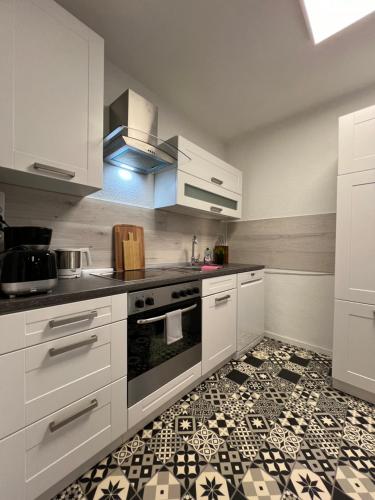 a kitchen with white cabinets and a tile floor at Moderne, helle Terrassenwohnung im Kurort in Bad Herrenalb