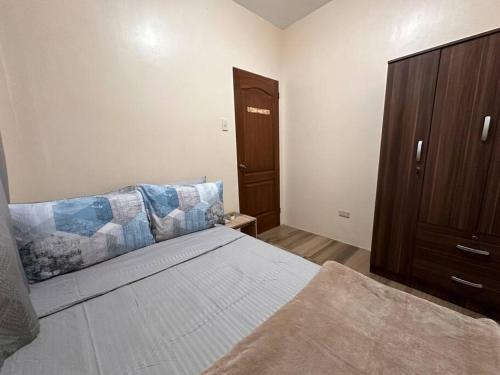 a bedroom with a bed and a wooden cabinet at Modern 1-bedroom Apartment with Full-Bed in Sibulan