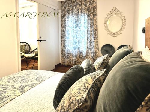 a bedroom with a bed with pillows and a mirror at As Carolinas in Isla de Arosa