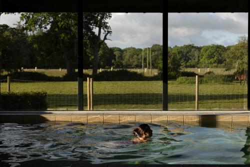 a woman is swimming in a swimming pool at New Park Manor Hotel in Brockenhurst