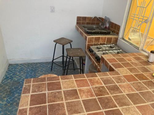 a kitchen with a counter and a stove and stools at Casa descanso las americas in Ecatepec