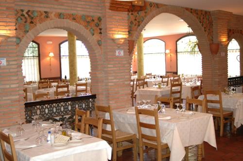 a restaurant with white tables and chairs and brick walls at Balneario Cervantes in Santa Cruz de Mudela