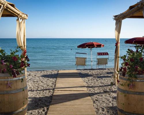 a pathway to the beach with chairs and umbrellas at Toscana Biovillage - Private Cottage in Cecina
