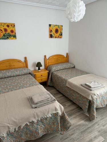 a room with two beds and a table with a lamp at Piso Los Jardines in Peñaranda de Bracamonte