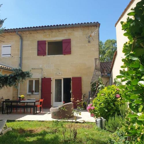 une maison avec des portes rouges et une table dans une cour dans l'établissement Maison en pierre avec jardin proche de Bordeaux, à Camblanes-et-Meynac