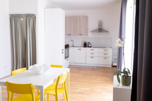 a kitchen and dining room with a white table and yellow chairs at FP Apartments Pizzo in Pizzo