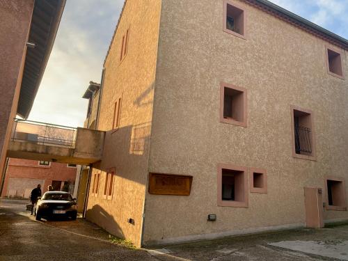 un bâtiment avec une voiture garée à côté dans l'établissement Escale à Aubenas, à Aubenas