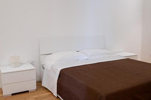 a white bedroom with a large bed and a white nightstand at FP Apartments Pizzo in Pizzo