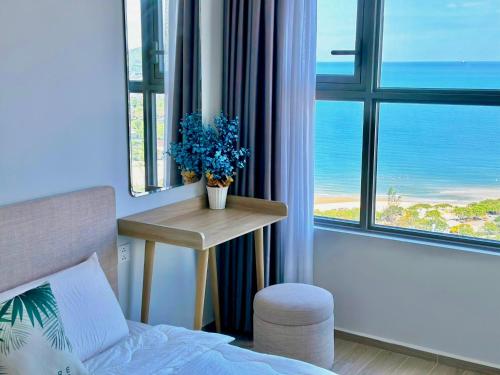 a bedroom with a bed and a table with a view of the ocean at The Sóng Hotel & Apartment Vũng Tàu in Vung Tau