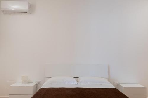 a white bedroom with a bed and two night stands at FP Apartments Pizzo in Pizzo
